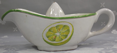 Side view of a gravy boat shape juicer with green and yellow lemon slice