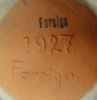 The basemark on an orange jug, green leaves and purple top ceramic juicer