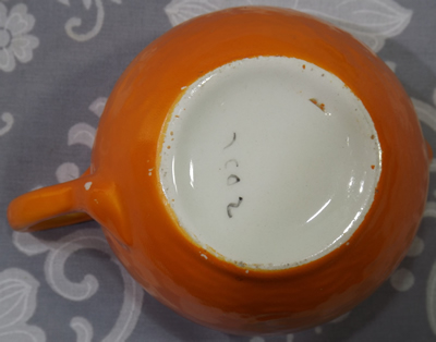 The base of an orange with orange & white top 2 piece ceramic juicer showing numbering