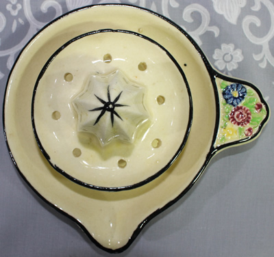 Top view of saucer juicer with central strainer and multicoloured flowers on handle