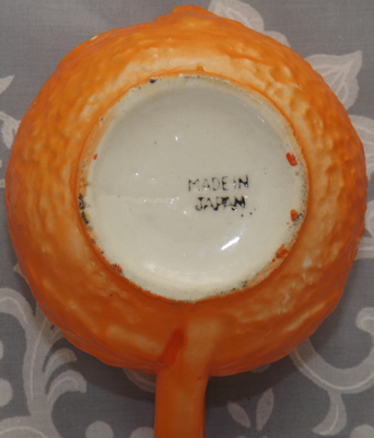 Base of the jug for an embossed flowers on an orange ceramic juicer 