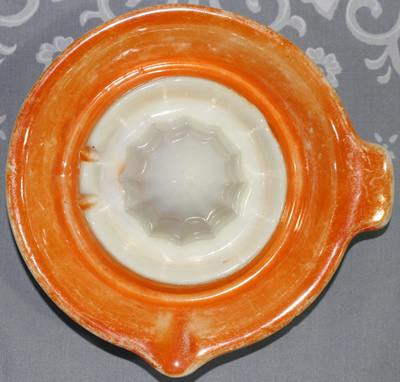 Top view of orange on white saucer shape juicer