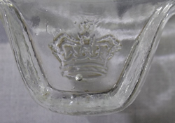 The crown on thumb grip and vine pattern around clear glass juicer 