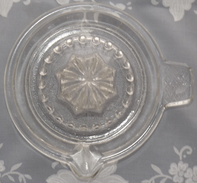 The top view of an embossed BRITISH ® MANUFACTURE clear glass saucer juicer