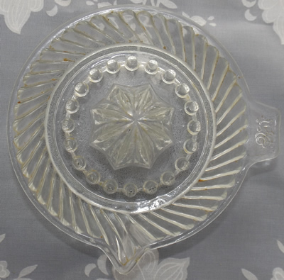 Top view of a dragon on tab handle sloping flutes pattern clear glass juicer