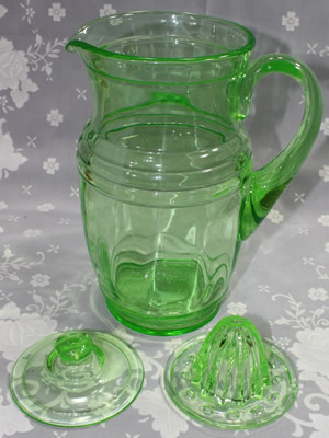 The 3 parts of a large green glass jug juicer with lid