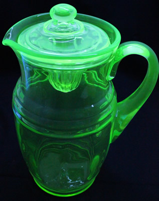 A large green glass jug juicer with lid under UV light