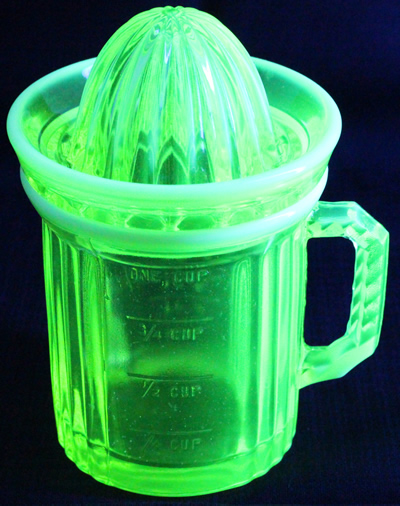 A frosted yellow Uranium Gillespie Measuring Cup with a reamer top juicer under UV light