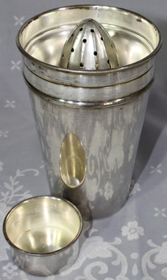 The juicer inserted in a hallmarked M.A. silverplate cocktail shaker with juicer