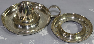 The 2 parts of a silver plate juicer with a loop handle