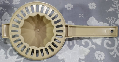 Bottom of a 1 piece beige plastic with handle juicer