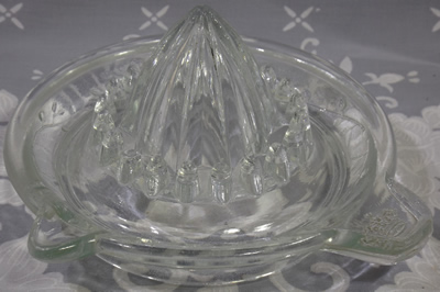 Crown on thumb grip and vine pattern around  clear glass juicer